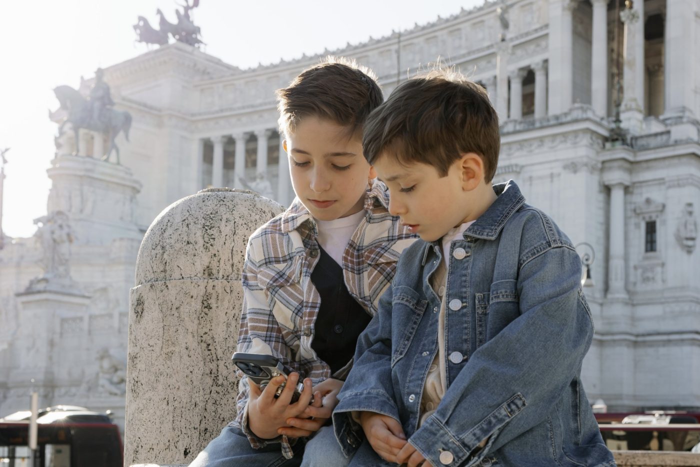 Due bambini guardano il telefono davanti al Vittoriano