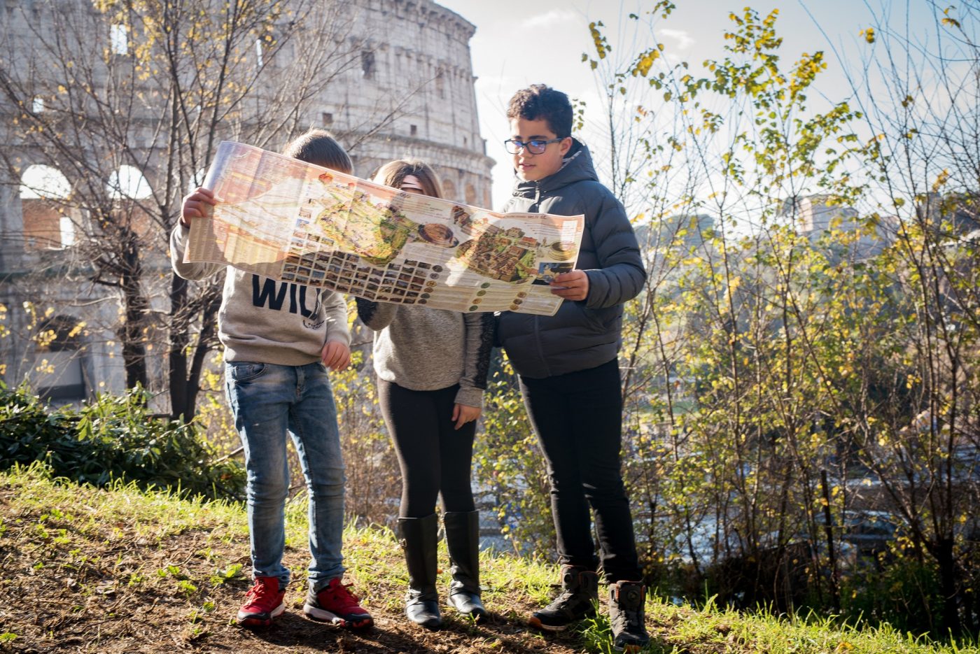 Un papà e i figli con la mappa su un colle romano