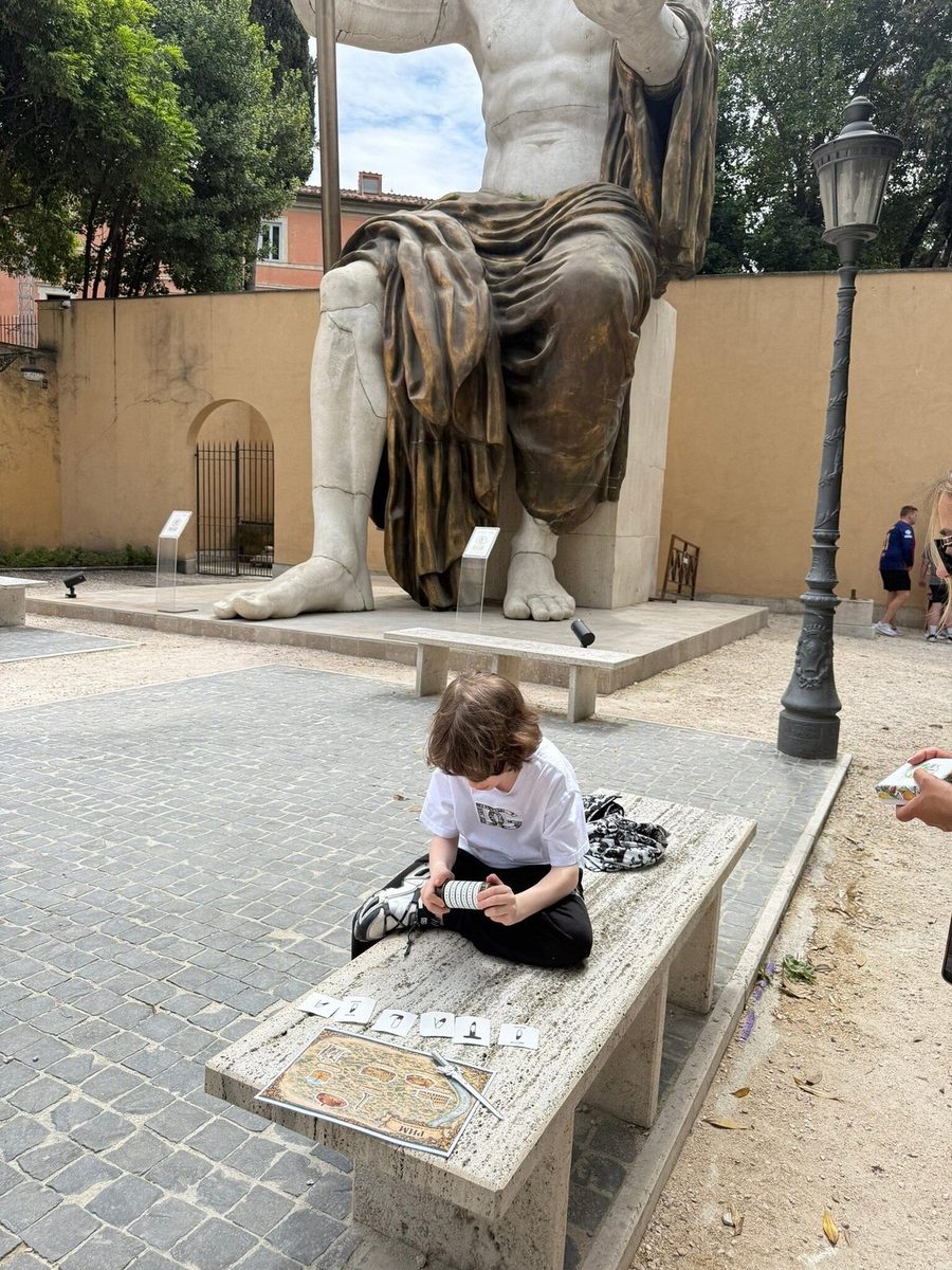 A child on a bench beside a colossal ancient statue