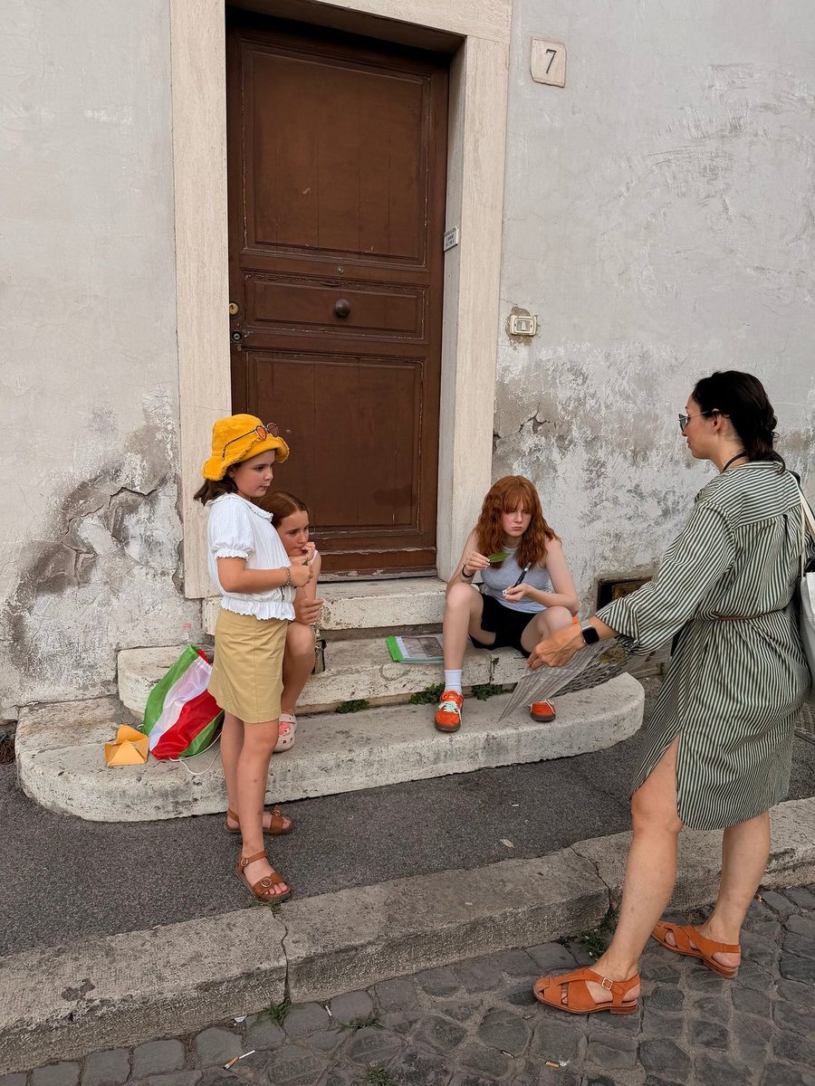 Children rest on the steps by the door of an old house