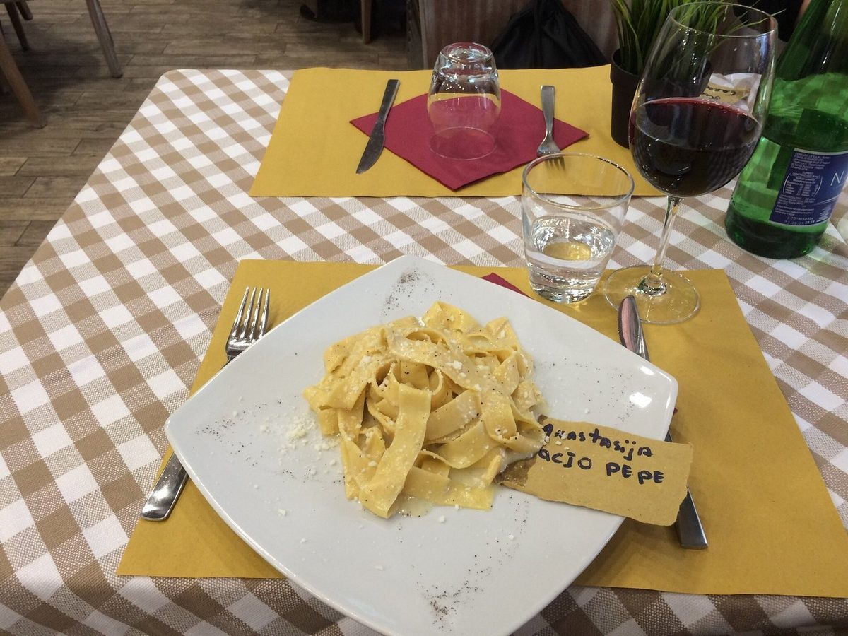 A plate of homemade pasta with a glass of wine