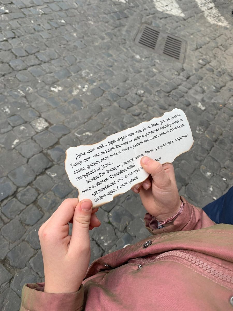 A hand holds a note with a quest task