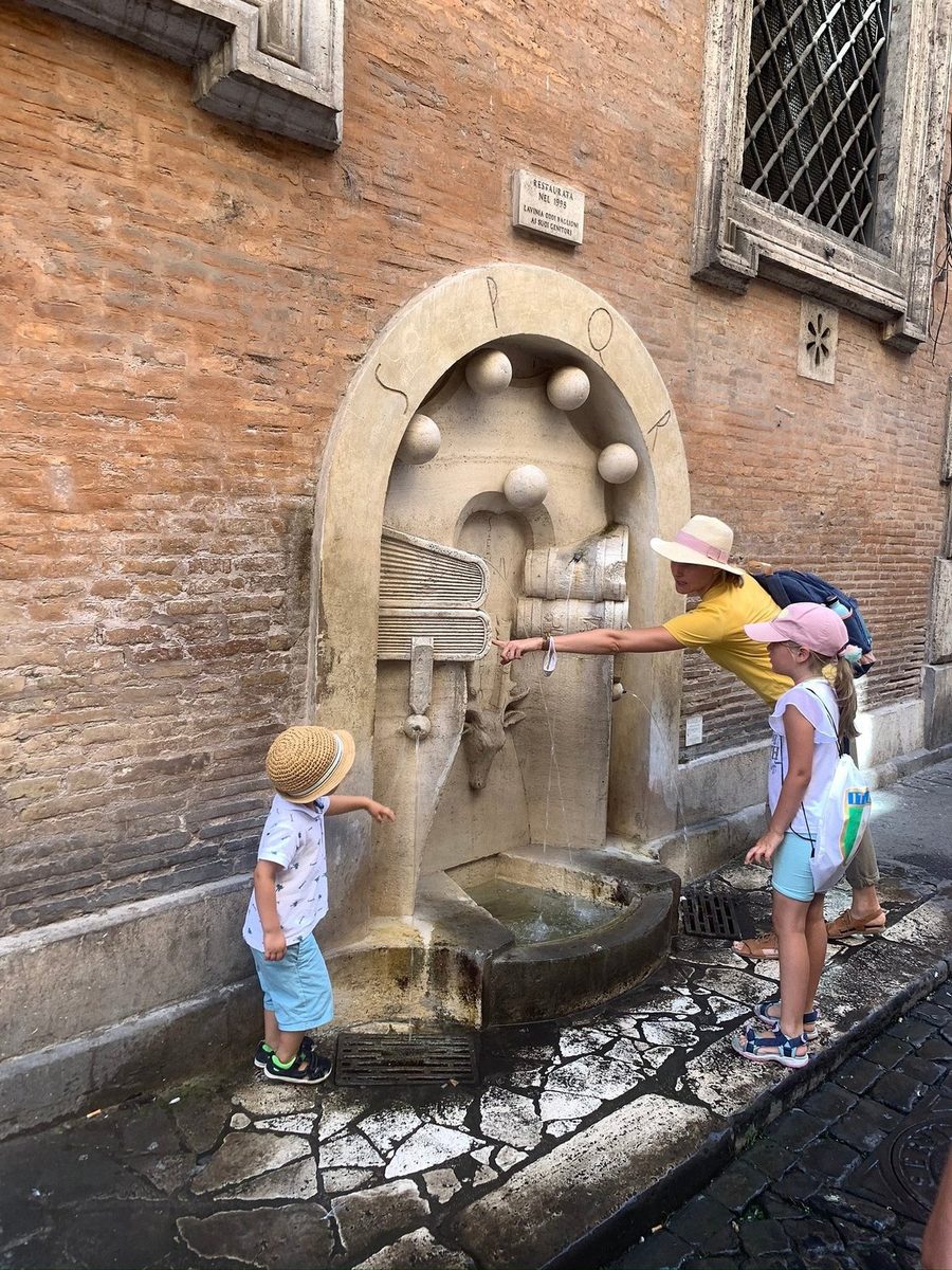 Children at a drinking fountain in a Roman street