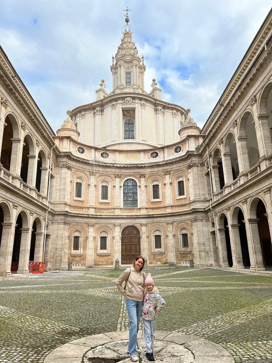 A girl in the courtyard of a baroque church with a spiral dome
