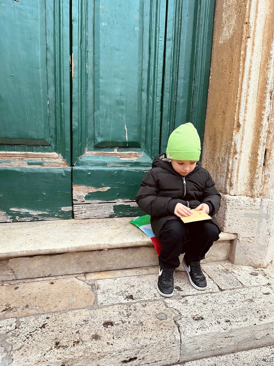 A child with the quest notebook on the steps by an old door