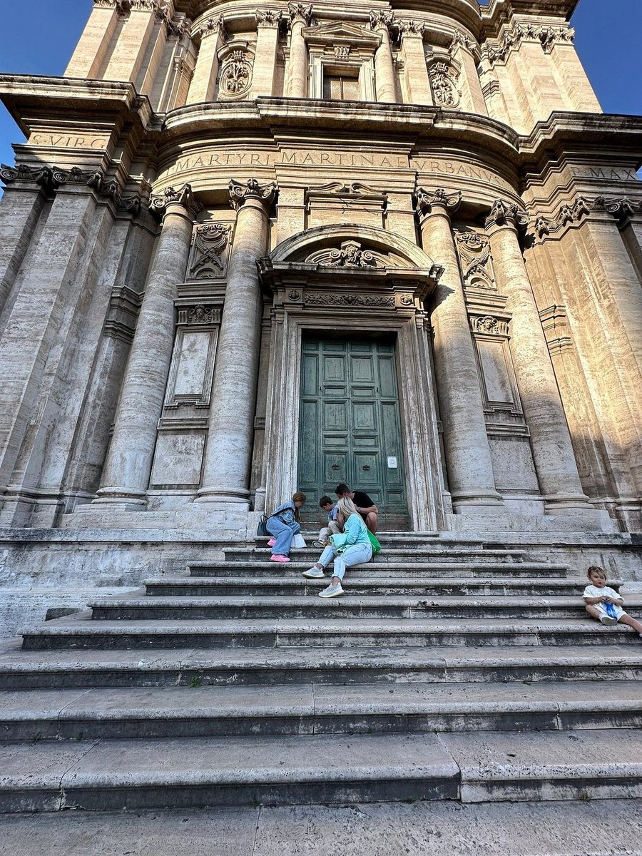 A baroque church facade, children on the steps