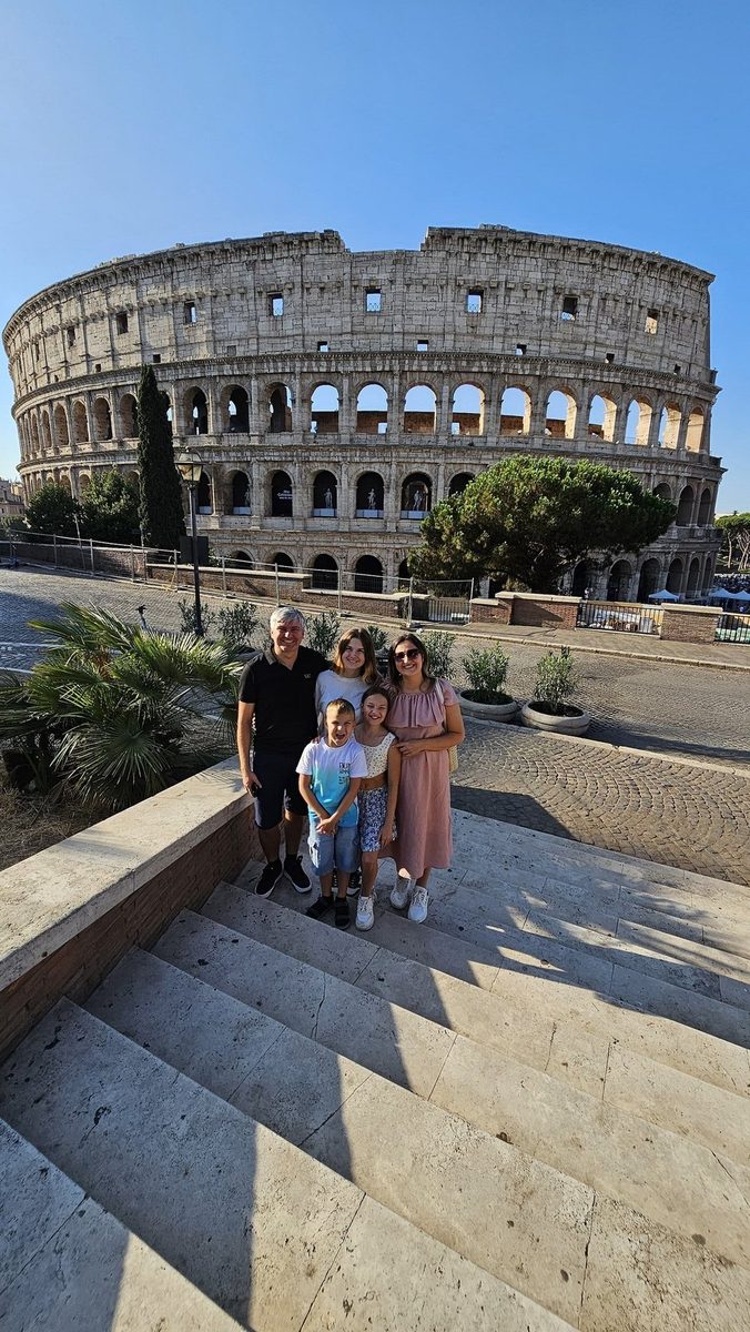 A family on the steps in front of the Colosseum