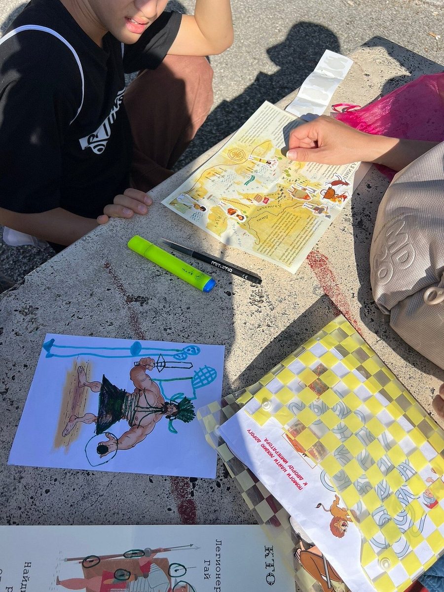 Children fill in the quest materials on a stone surface